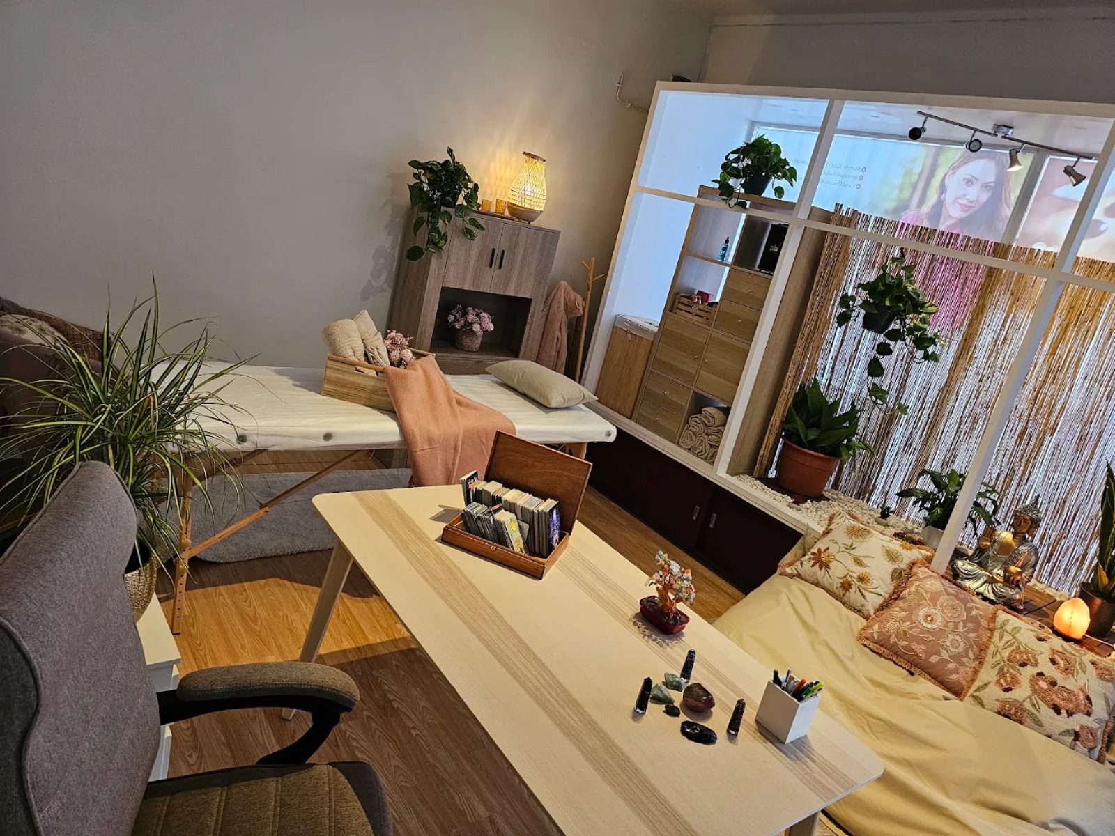 Vista ampla da sala com mesa de massagem, mesa de trabalho e canto zen